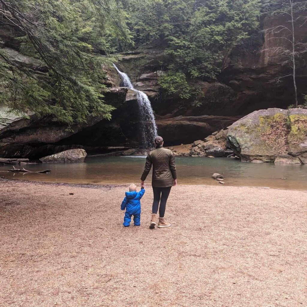 Woman and child walking toward waterfall