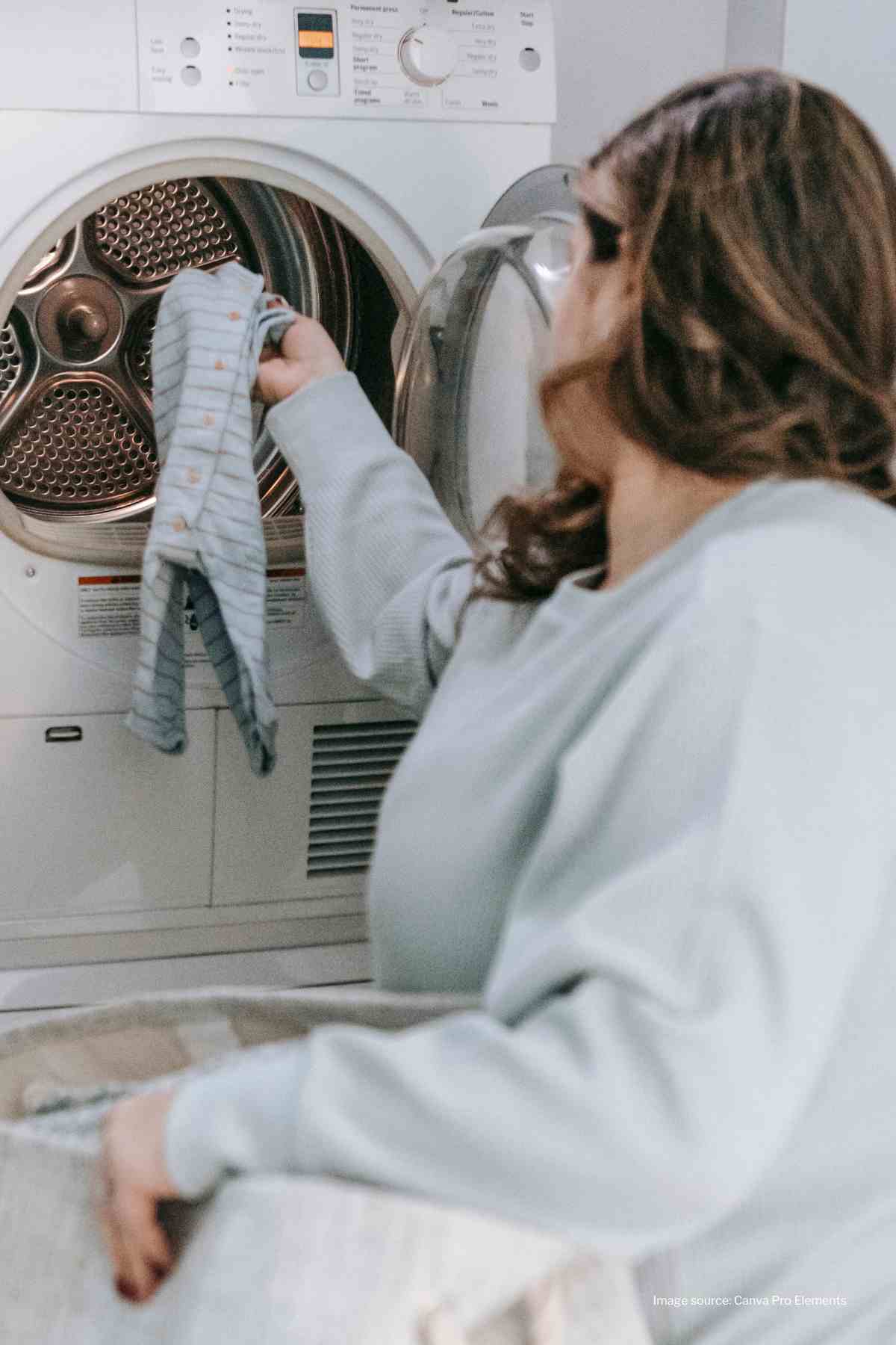 Woman holding laundry basket placing baby clothes into a washing machine