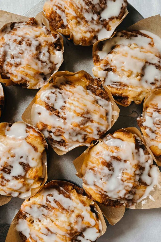 Sourdough coffee cake muffins with vanilla glaze in bakery style brown paper baking cups in metal muffin tin
