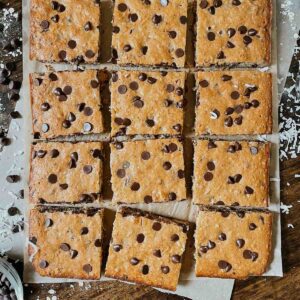 Sourdough cowboy cookie bars cut into squares on parchment paper on wooden table