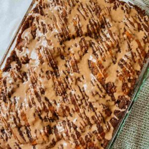 Sourdough pumpkin coffee cake drizzled with cinnamon vanilla glaze in a glass baking pan