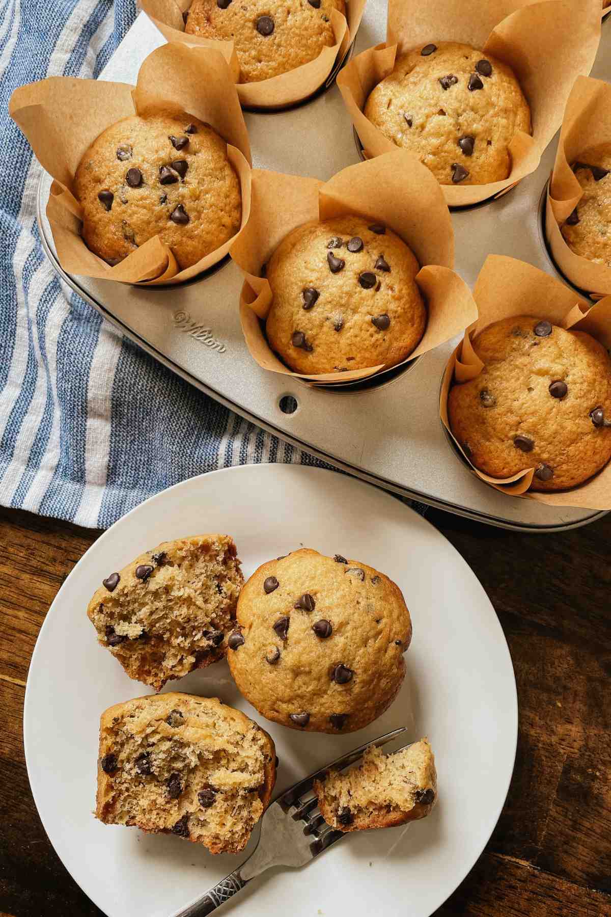 Sourdough banana bread muffins on a white plate with a fork with muffin tin of muffins behind