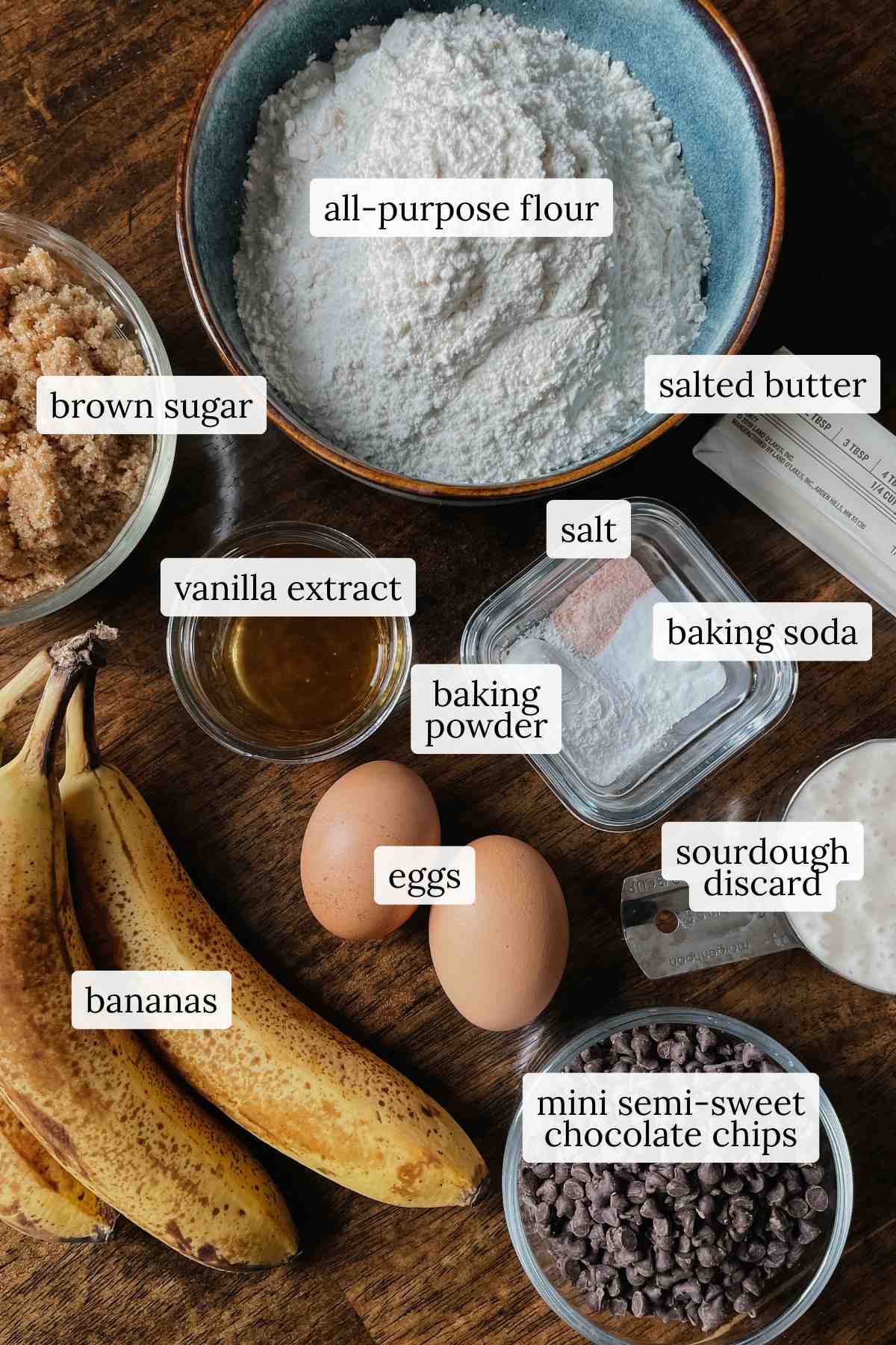 Ingredients for sourdough banana bread muffins labeled on a wooden table