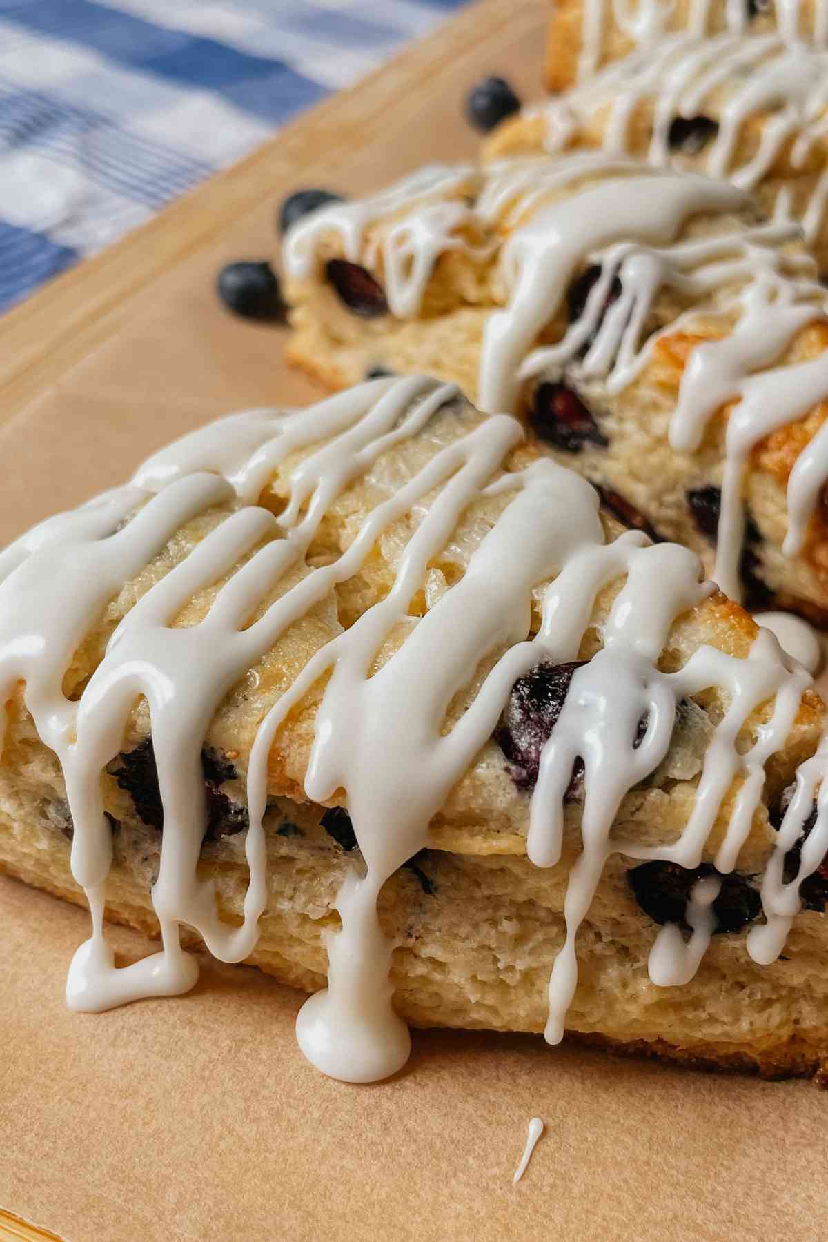 Close up of a sourdough blueberry scone with dripping vanilla glaze