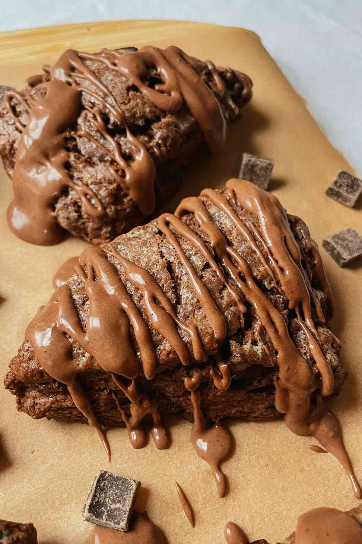 Chocolate sourdough scone drizzled with chocolate glaze on parchment paper