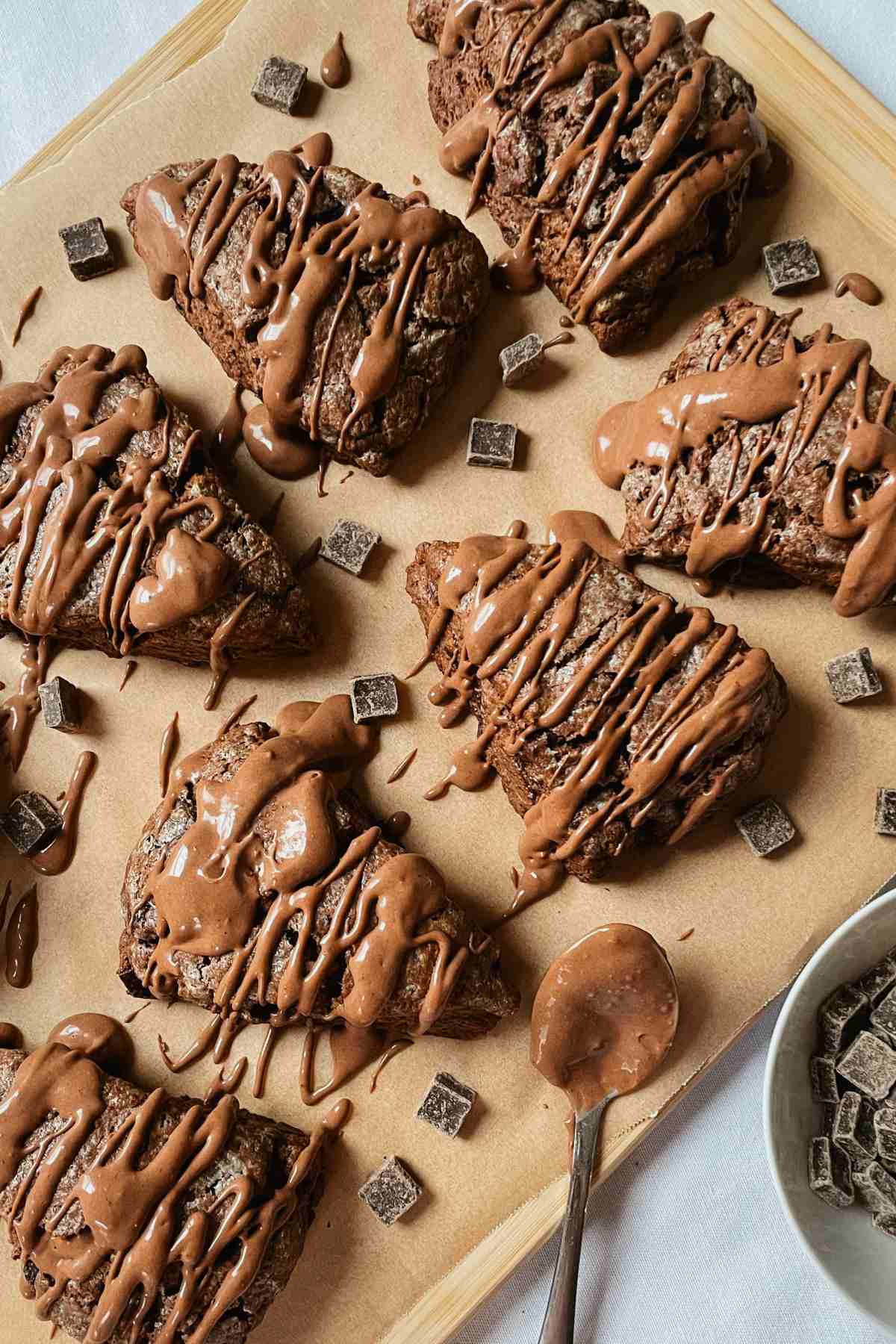 Chocolate sourdough scones drizzled with chocolate glaze and chocolate chunks scattered around