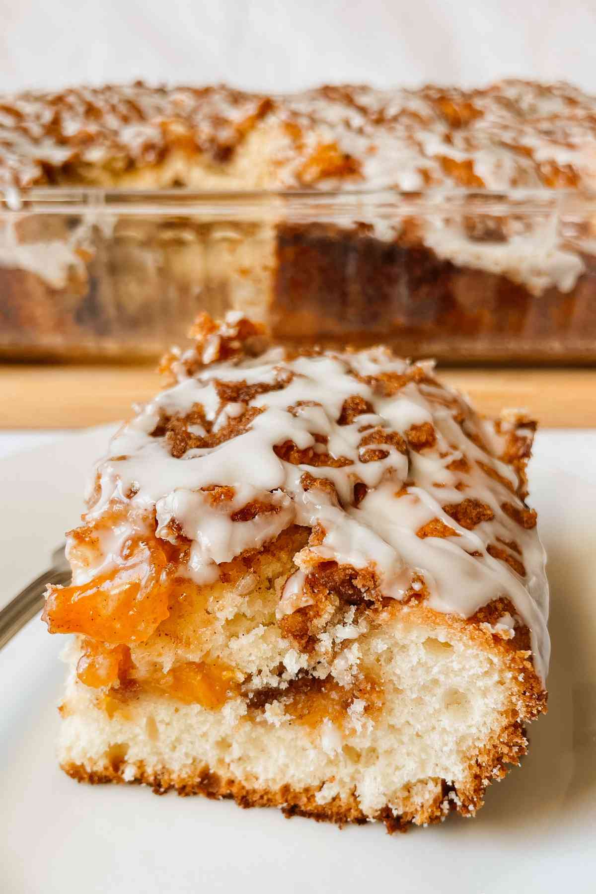 Sourdough peach coffee cake piece drizzled with vanilla glaze