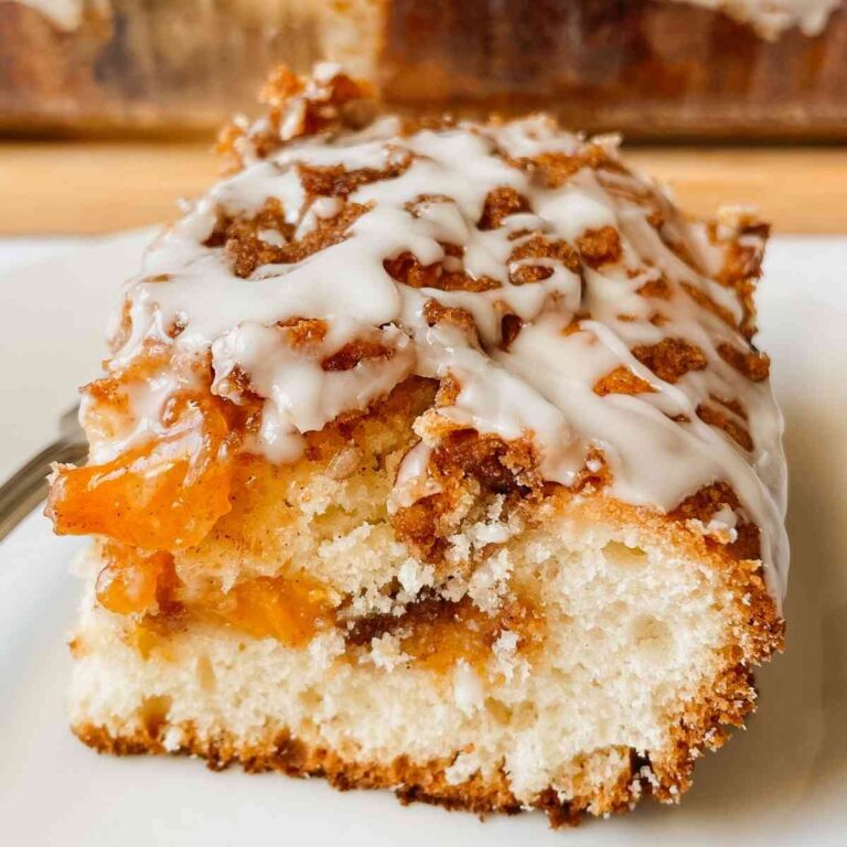 Sourdough peach coffee cake piece drizzled with vanilla glaze