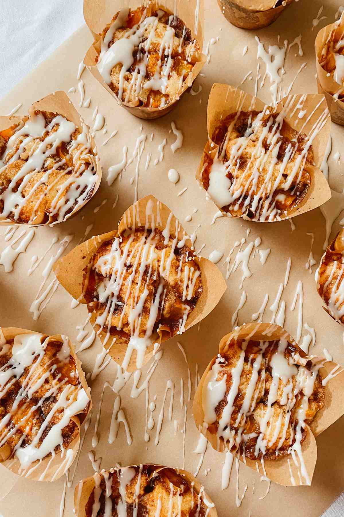 Sourdough peach coffee cake muffins drizzled with vanilla glaze