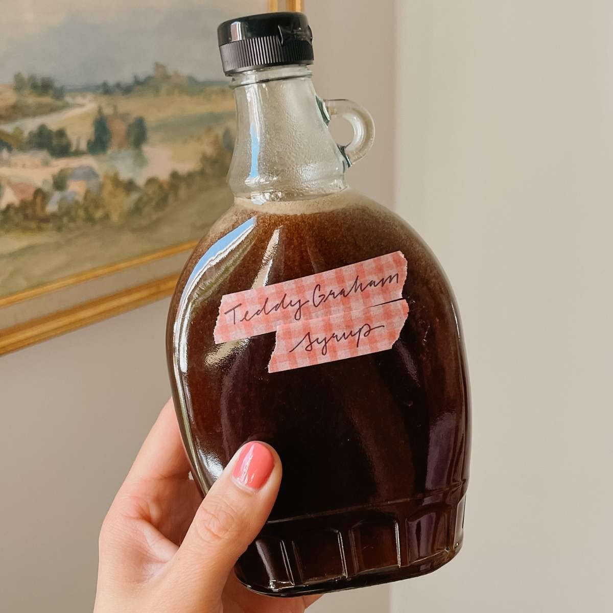 Hand holding teddy graham latte coffee syrup in glass bottle