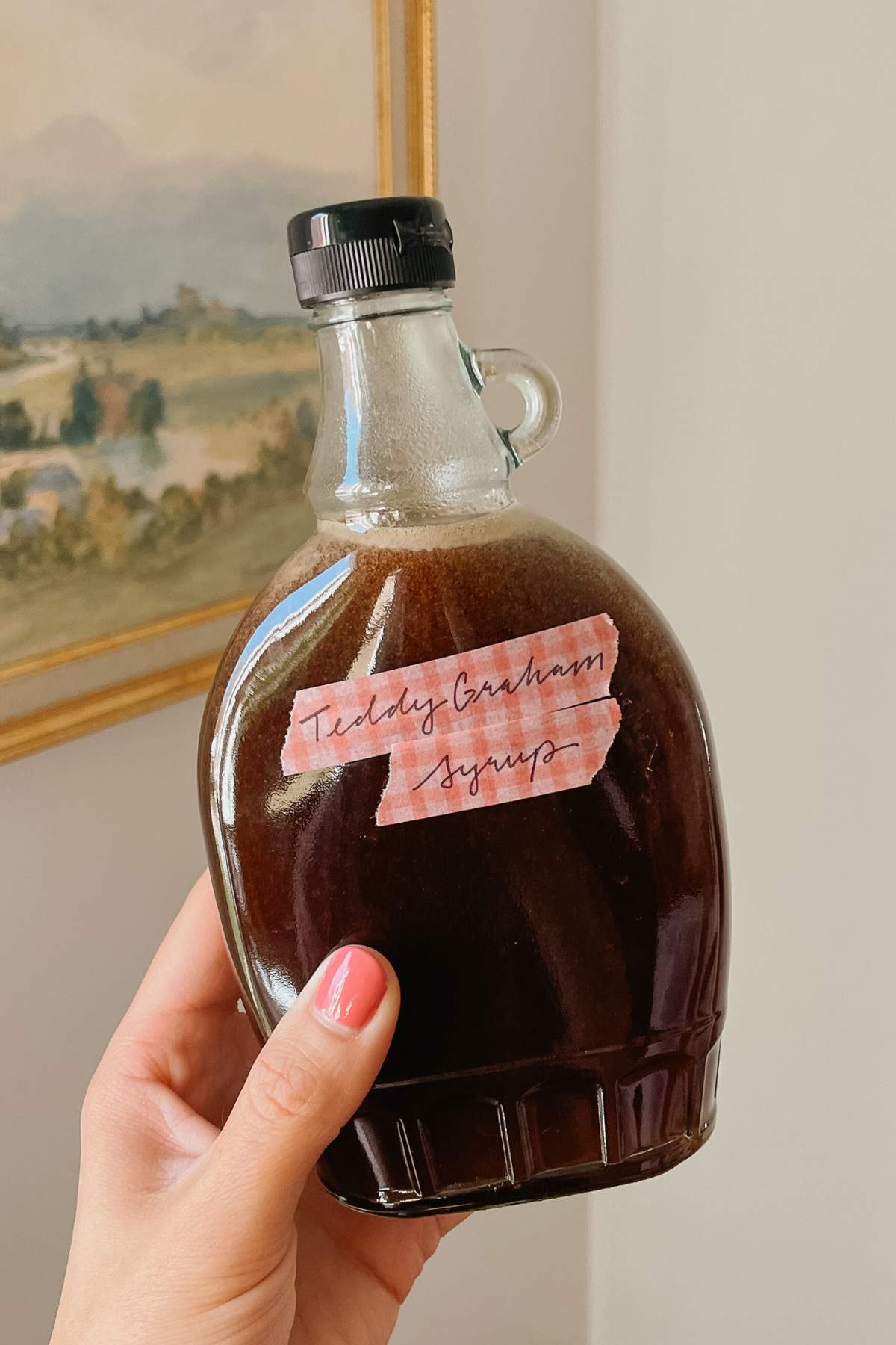 Hand holding teddy graham latte coffee syrup in glass bottle