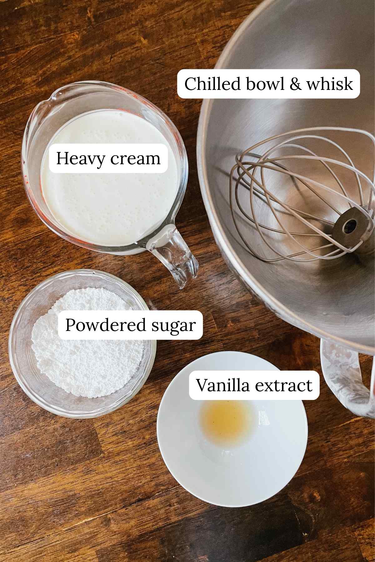 Homemade whipped cream recipe ingredients in bowls and labeled on wooden table