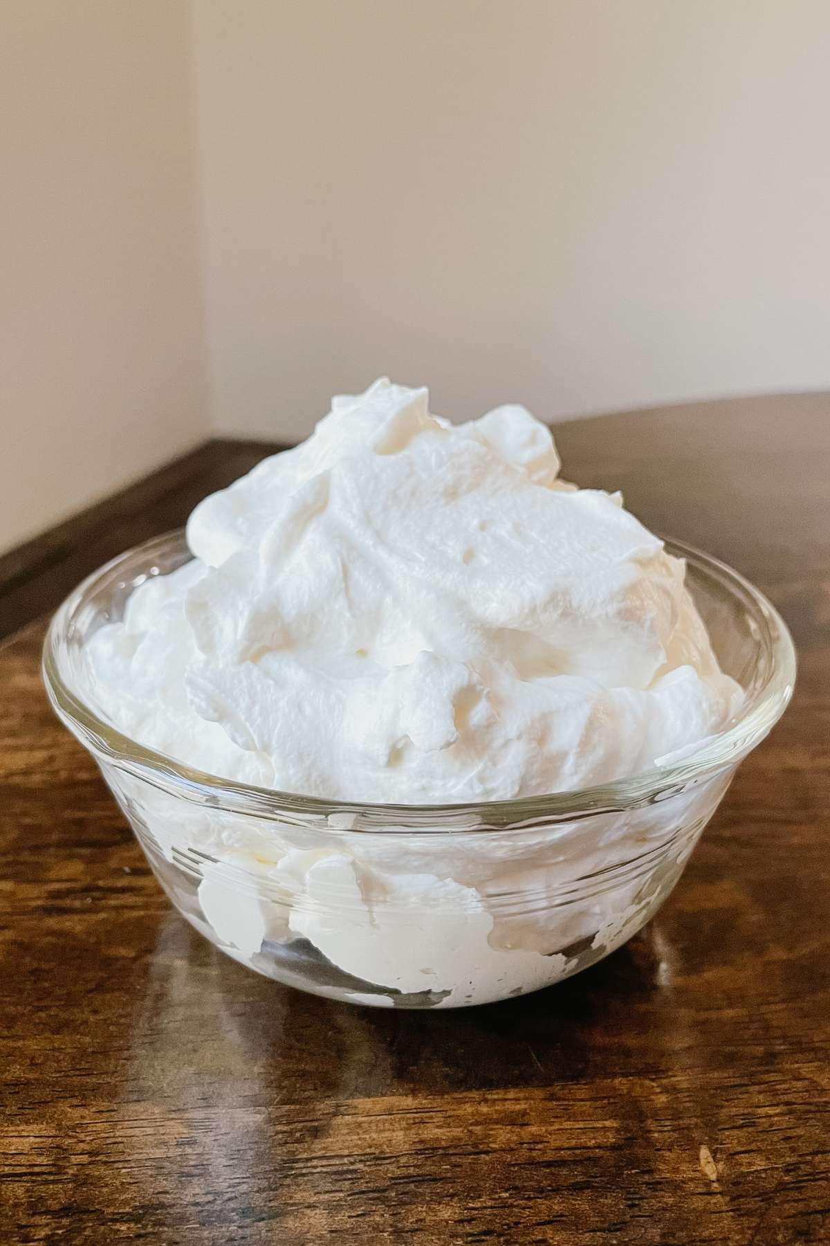 Homemade whipped cream in glass bowl sitting on wooden table