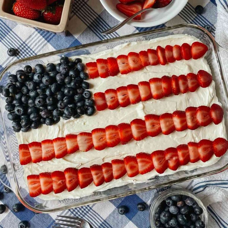 Sourdough American flag cake on blue checkered tablecloth with blueberries and strawberries in bowls