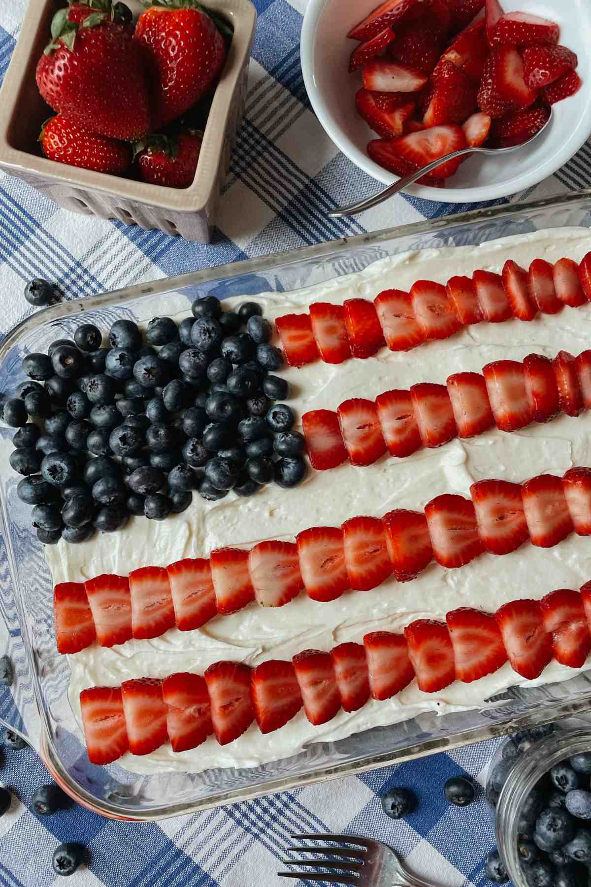 Sourdough American flag shortcake on blue checkered tablecloth with blueberries and strawberries in bowls