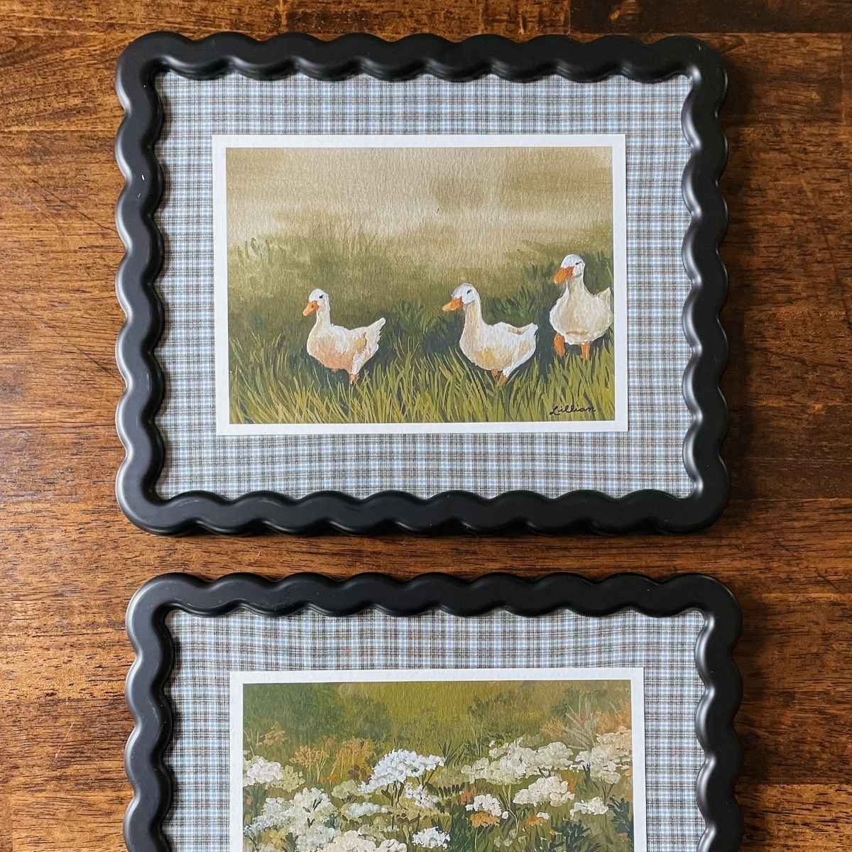 Black wavy picture frames with plaid fabric picture frame mats and art print of ducks and wildflowers
