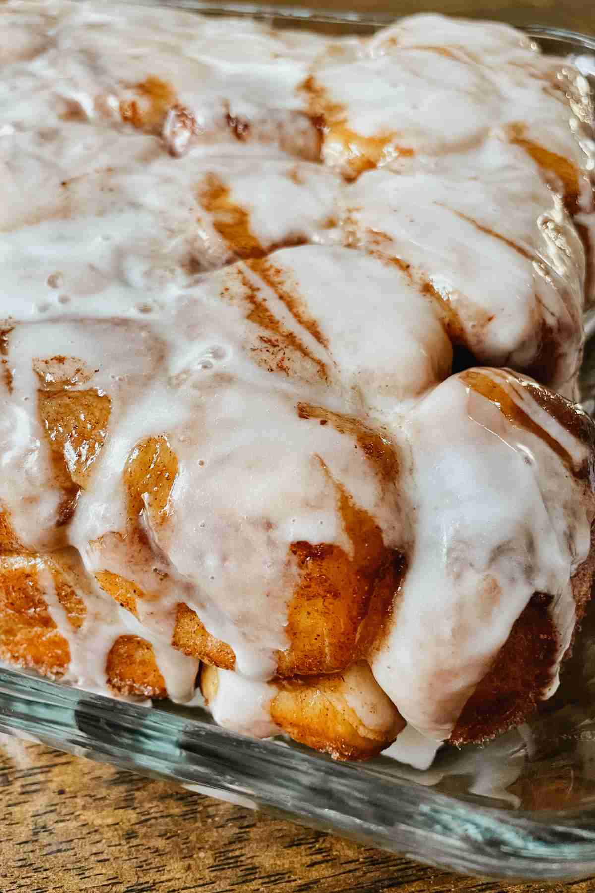 Sourdough monkey bread drizzled with vanilla icing in glass pan