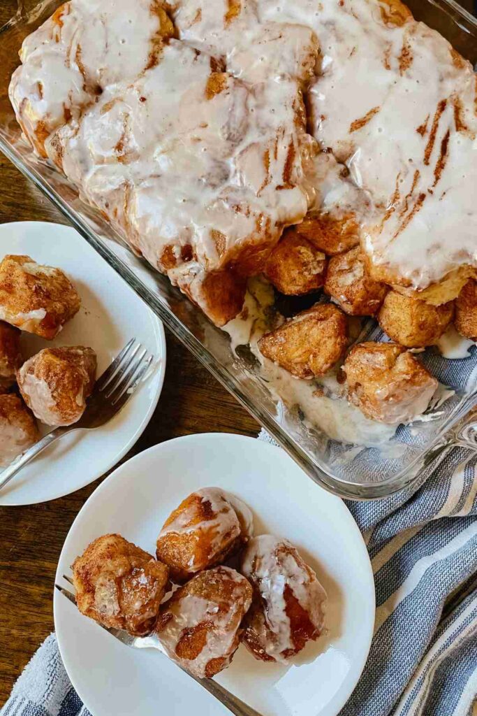 Sourdough monkey bread drizzled with vanilla icing in glass pan and served on white plates with forks