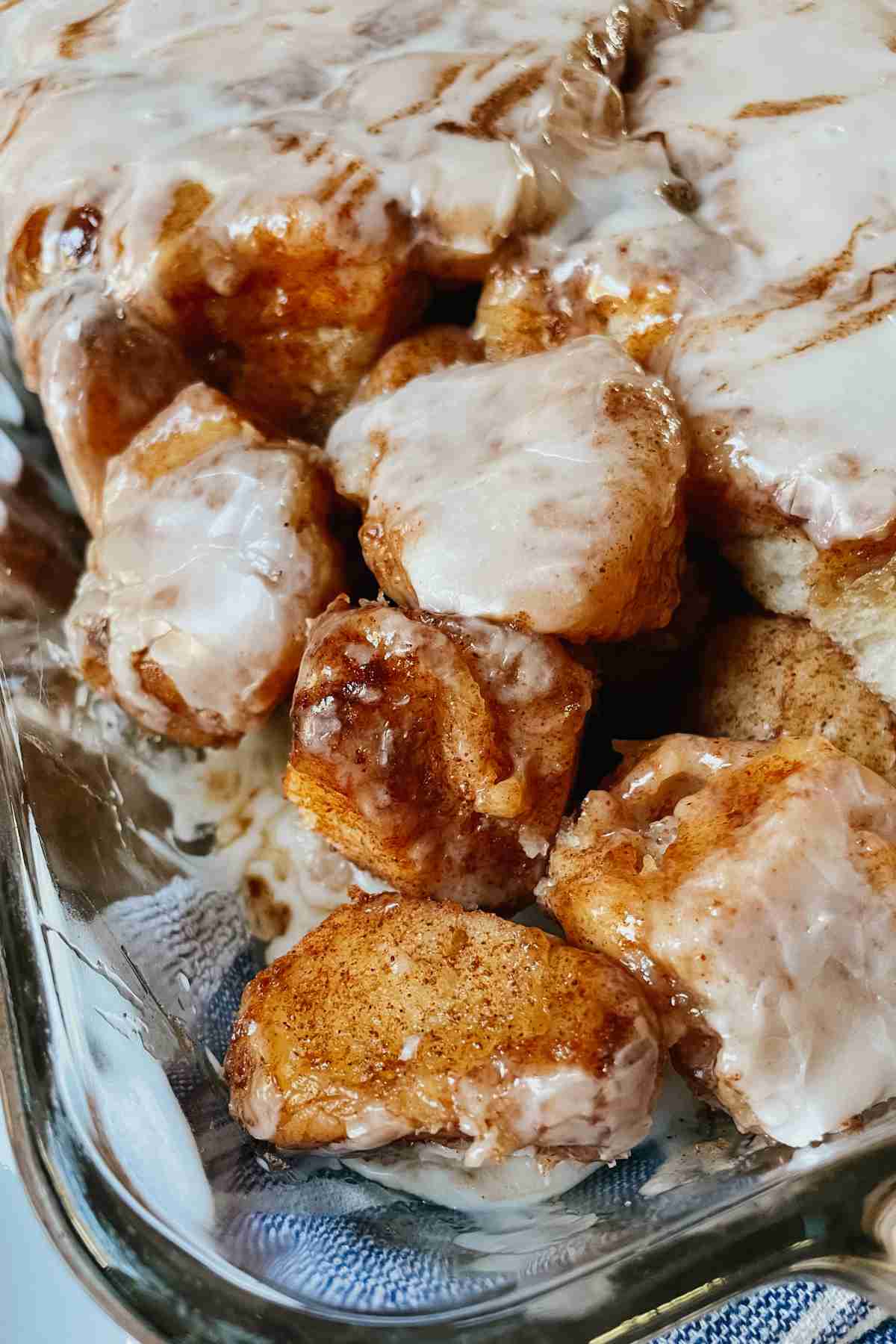 Sourdough monkey bread pieces drizzled with vanilla icing in glass pan