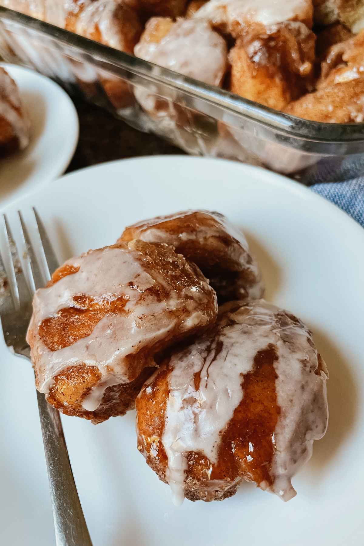 Sourdough monkey bread pieces drizzled with vanilla icing on white plate with a fork