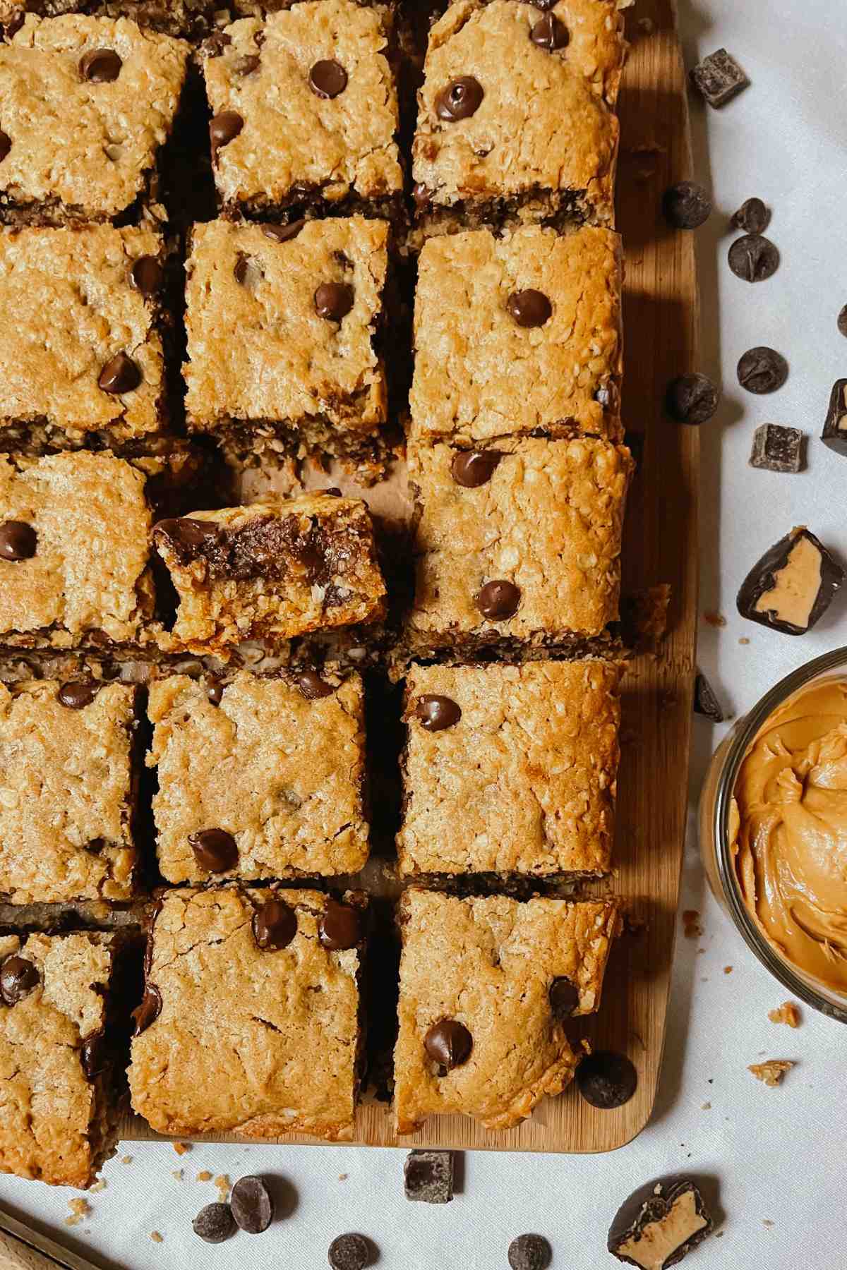 Sourdough peanut butter oatmeal chocolate chip cookie bars cut into squares on wooden cutting board