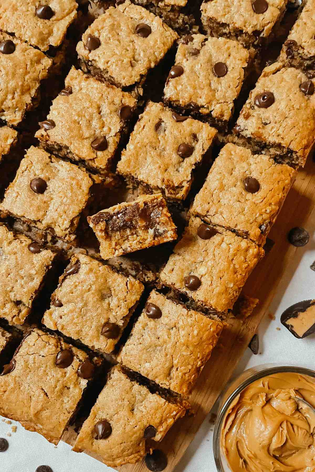 Chewy sourdough peanut butter oatmeal chocolate chip cookie bars cut into squares on wooden cutting board