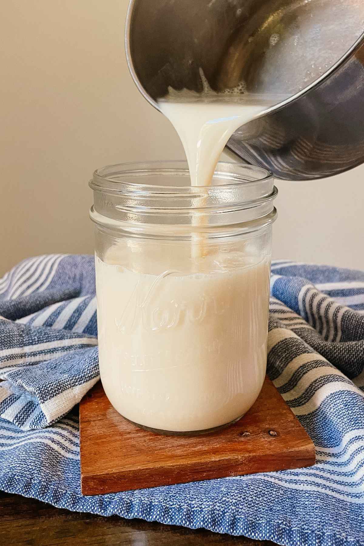 Crème brûlée coffee syrup being poured from a pot into a glass jar