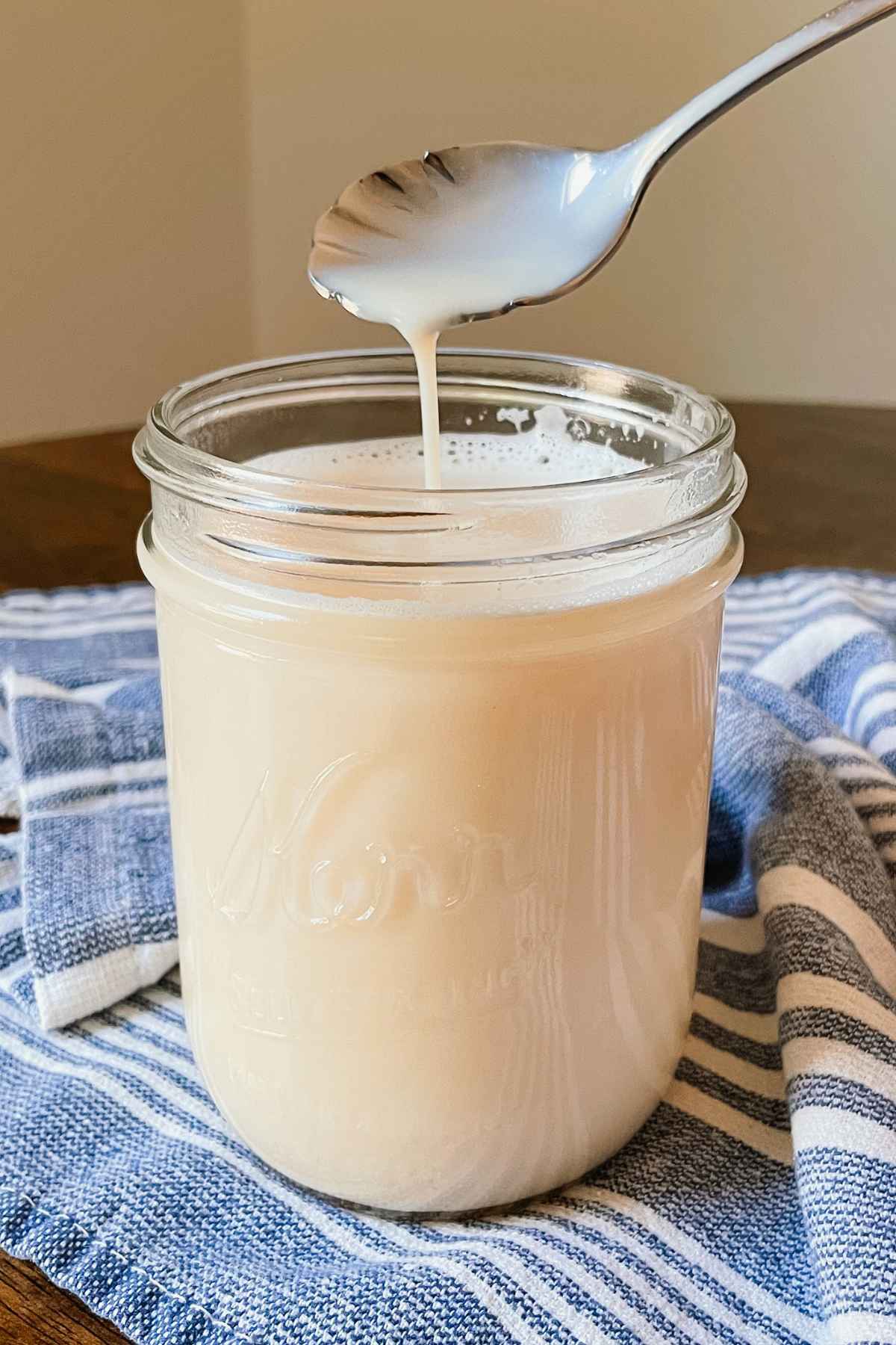 Crème brûlée coffee syrup in a glass mason jar with a silver spoon