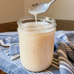 Crème brûlée coffee syrup in a glass mason jar with a silver spoon