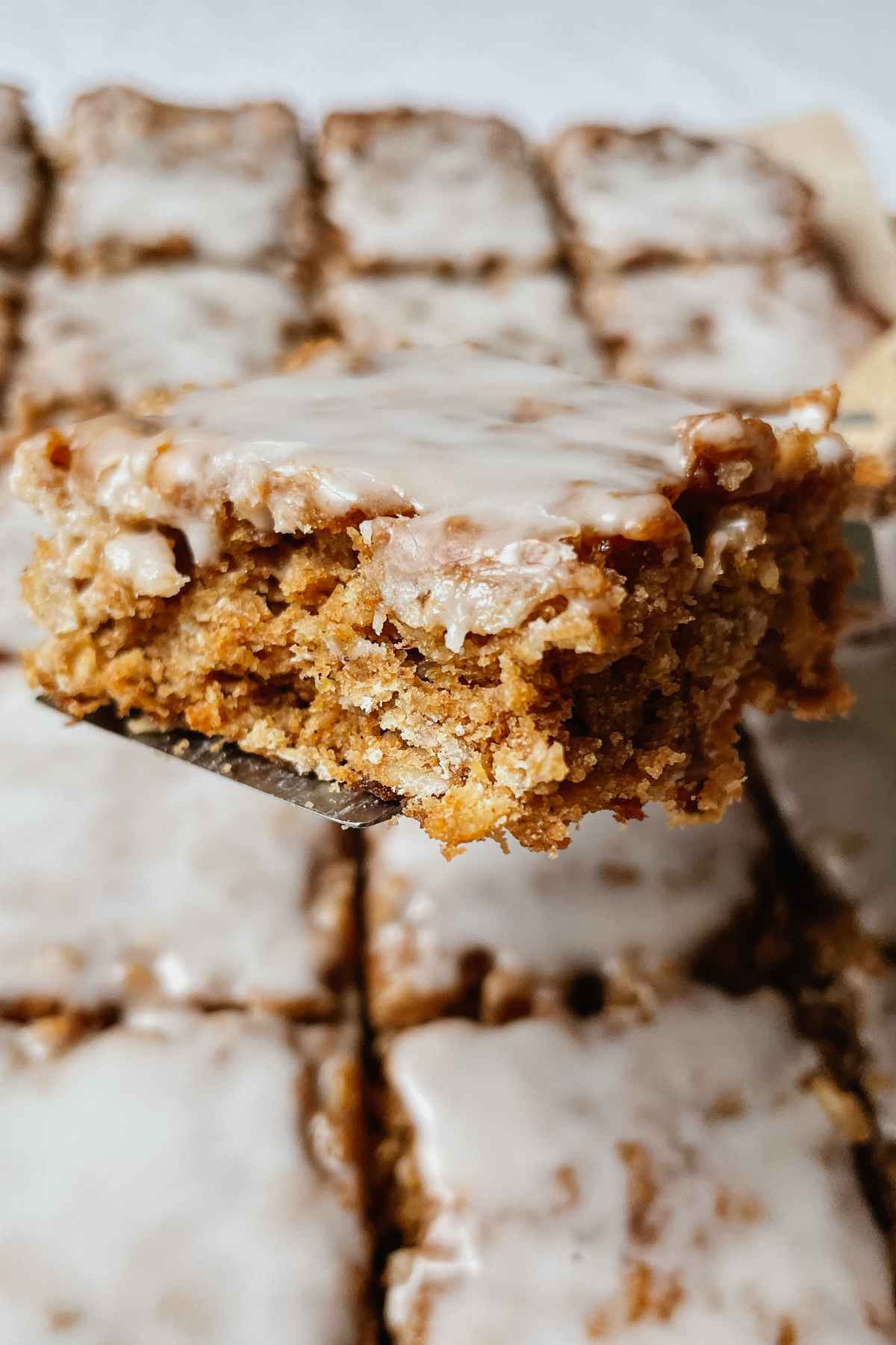 Sourdough iced oatmeal cookie bar square held up on a square server