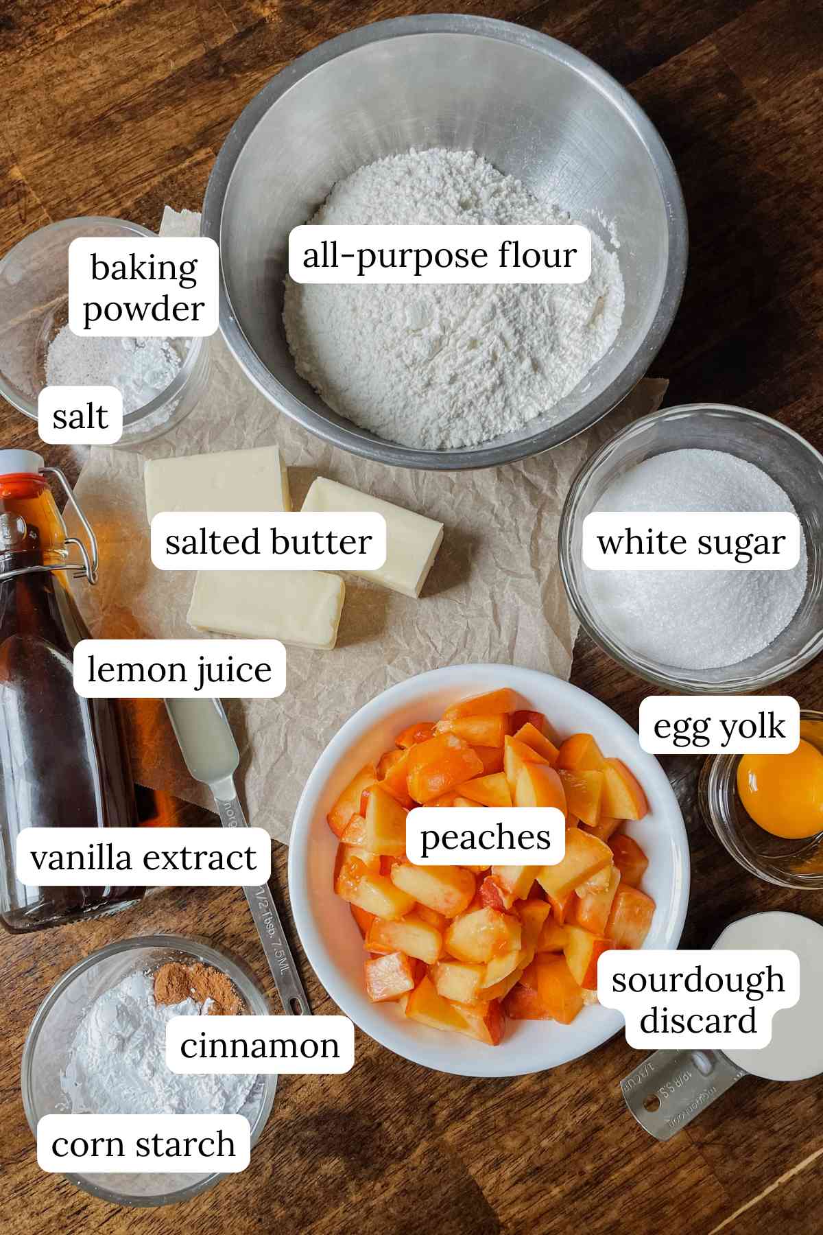 Ingredients for sourdough peach crumb bars labeled in bowls on a wooden table