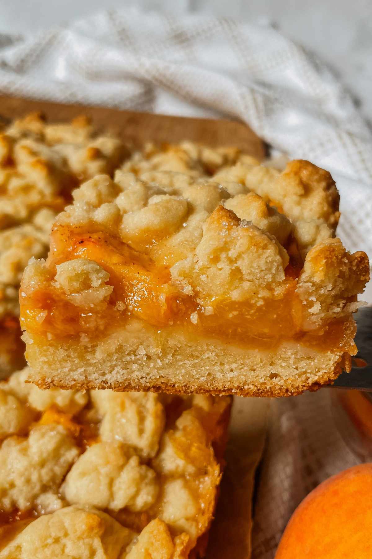 Sourdough peach crumb bar square held up on a square server