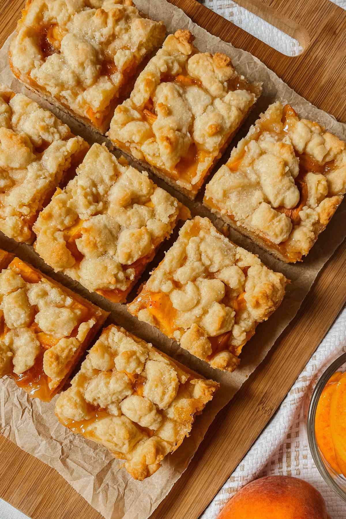 Sourdough peach crumb bars cut into squares on parchment paper on wooden cutting board