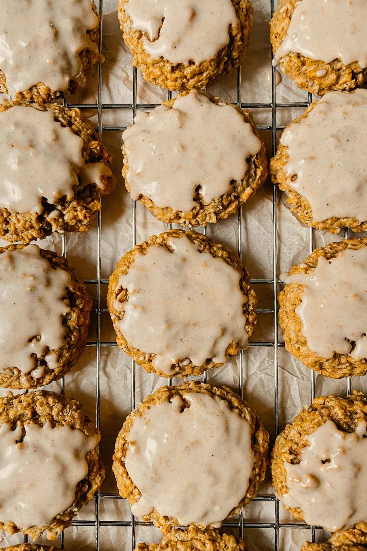 Sourdough pumpkin iced oatmeal cookies on wire cooling rack with brown parchment paper behind