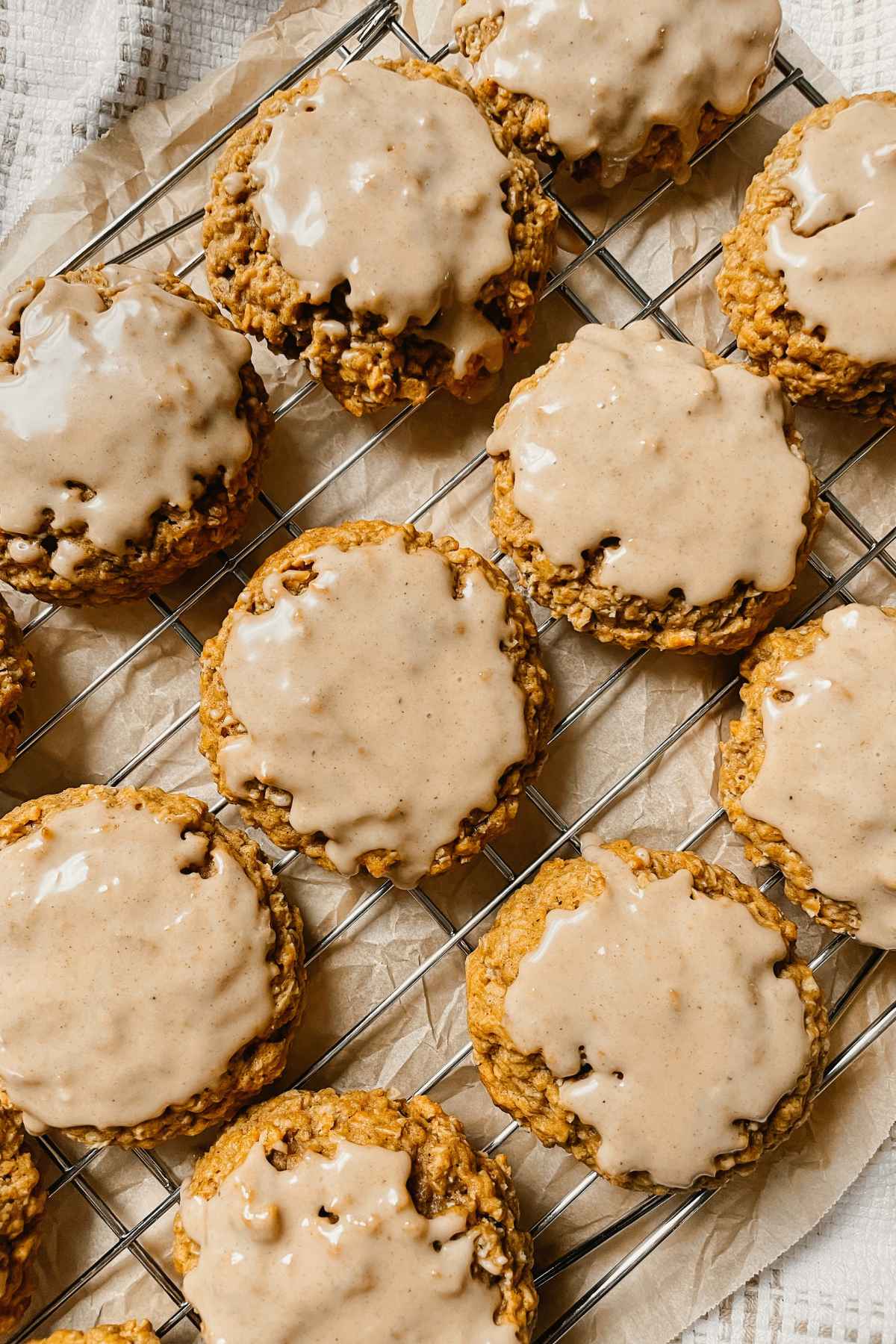 Sourdough pumpkin iced oatmeal cookies on wire cooling rack with brown parchment paper behind